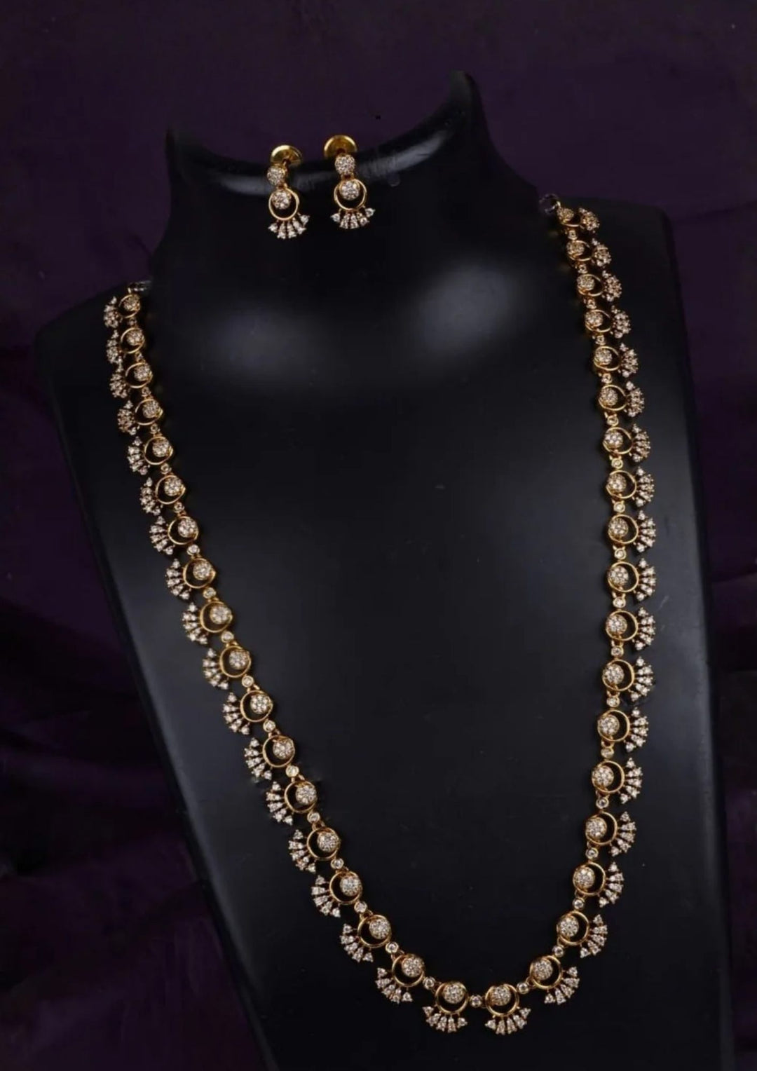  gold plated long haram necklace set highlighting a continuous single-strand link design. Each link features a brilliant round solitaire white zircon crystal nestled within a delicate, stone-studded crescent moon outline. The set includes a matching pair of two-tier hanging drop earrings that mirror the exact same celestial pattern.