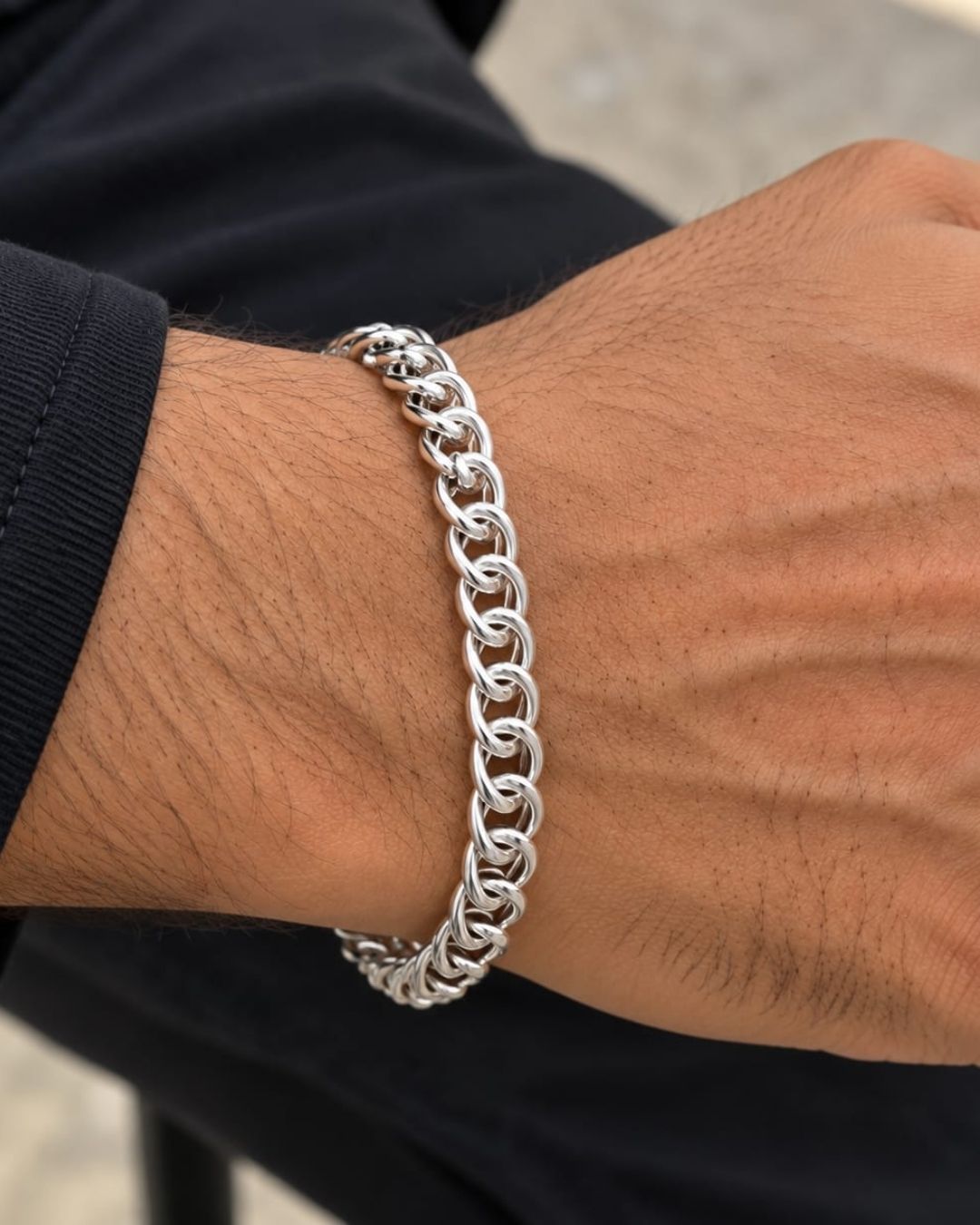 Stylish men’s silver finish bracelet arranged in a circular shape on a black background, highlighting its detailed chain design.
