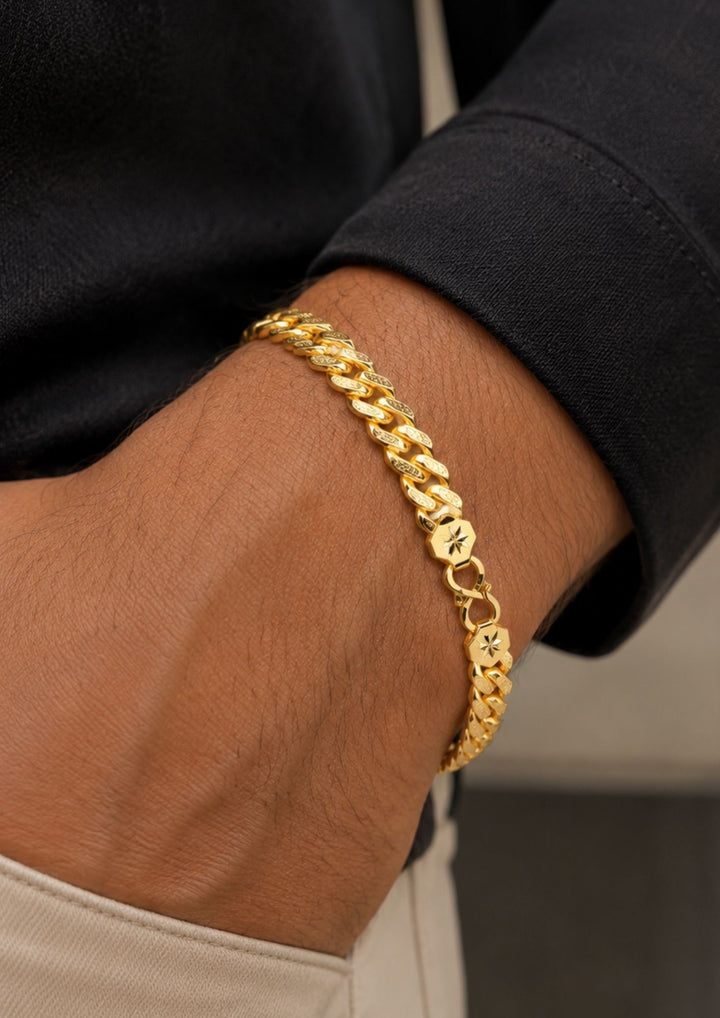 A close-up of a gold Cuban link chain bracelet worn on a person&