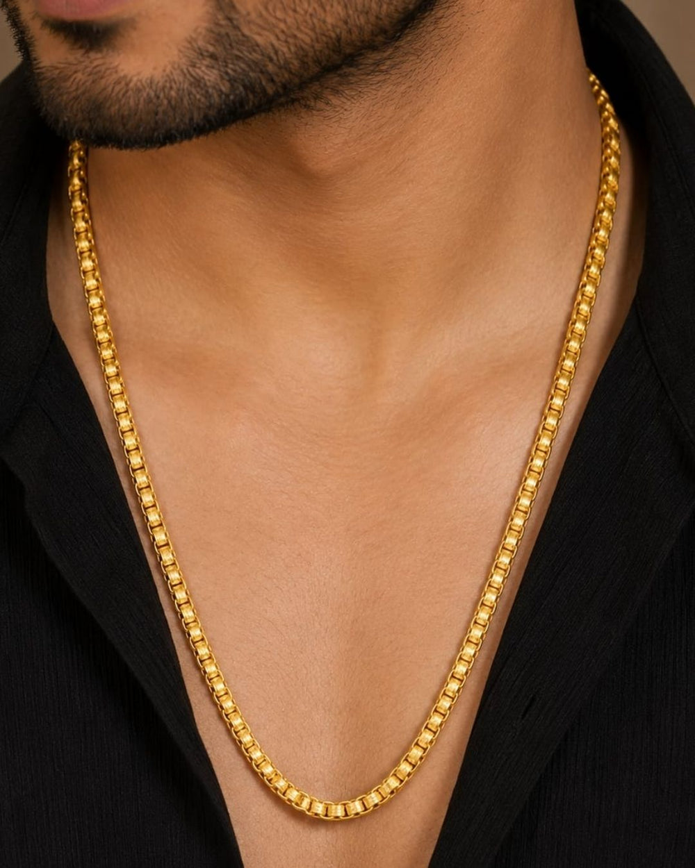 A gold-plated men's chain necklace arranged in a U-shape on a dark wooden surface, with decorative dried flower buds and a brass object in the background. White text in the upper left reads 'Men's Chain Gold Plated'.