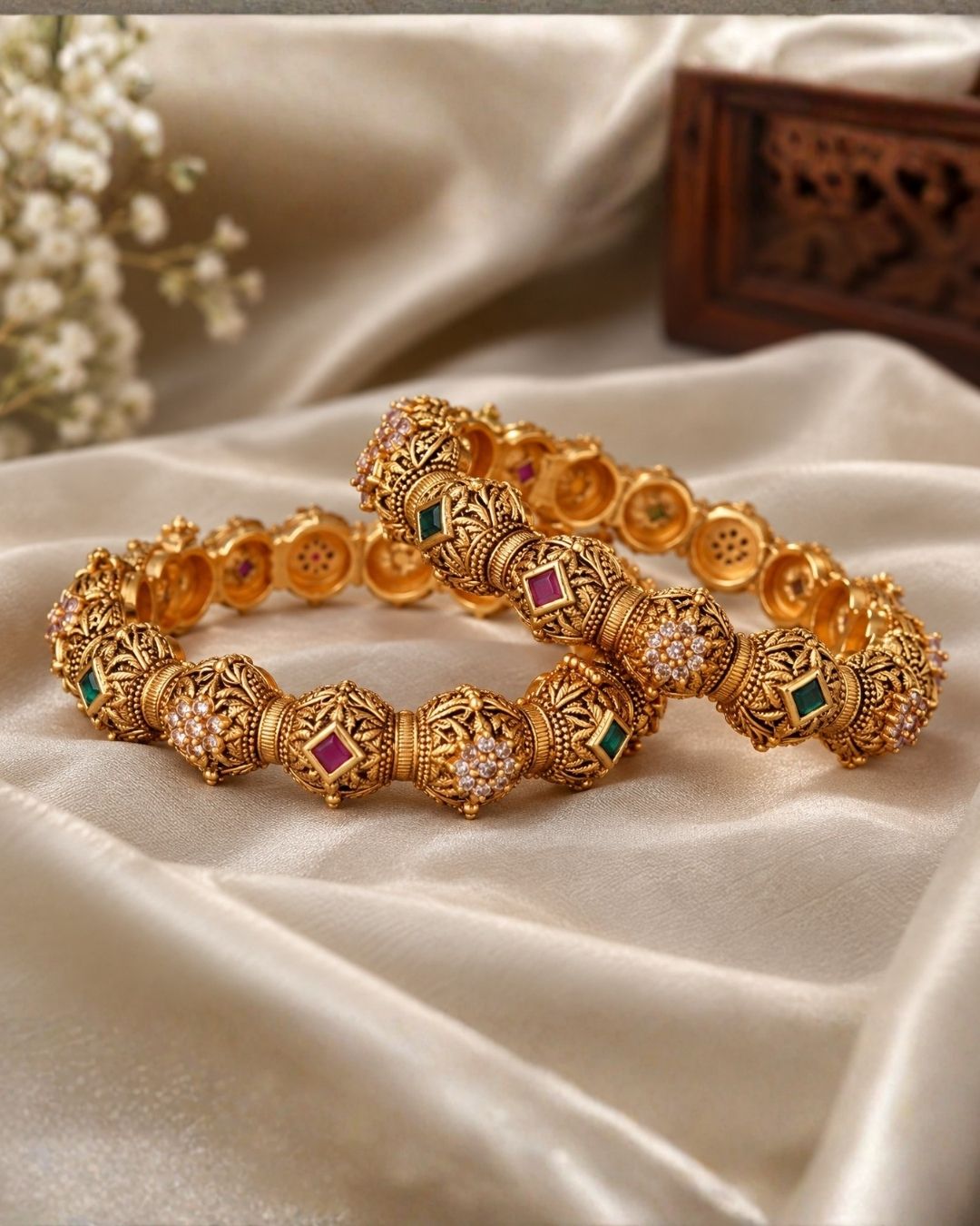 Traditional gold plated temple bangles showcasing ornate antique detailing, ruby pink square stones, emerald green accents, and floral zircon motifs. Perfect for bridal wear, festive occasions, and ethnic celebrations, offering a luxurious heritage-inspired look.