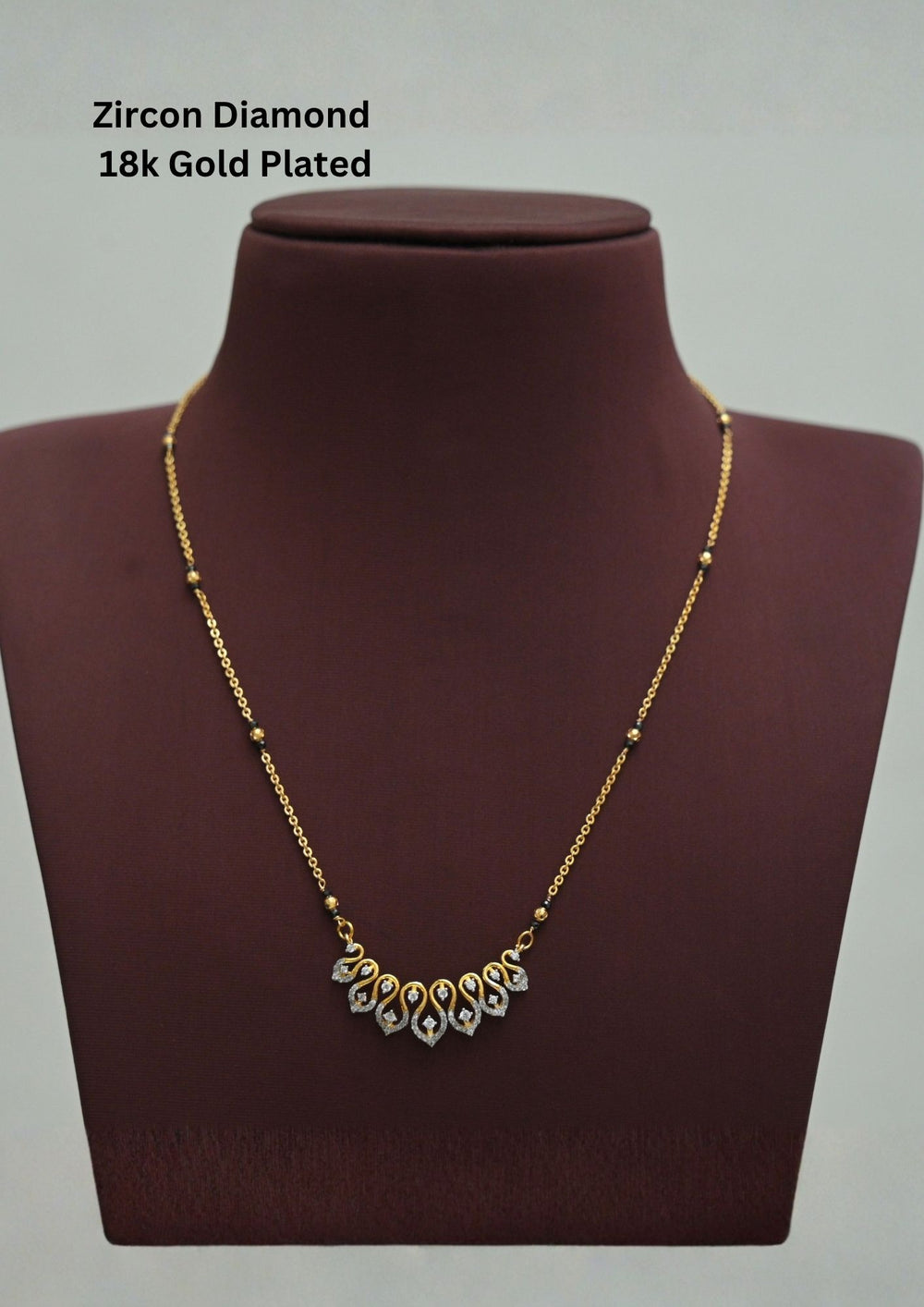 Modern Zircon Diamond gold plated mangalsutra necklace The design features a delicate gold link chain transitioning into sections of traditional small black beads on both sides. The central pendant showcases a sleek, contemporary curved V-shape and a stylized butterfly or floral motif encrusted with sparkling white cubic zirconia stones. This elegant neckpiece perfect for daily wear, office wear, and casual outfits.