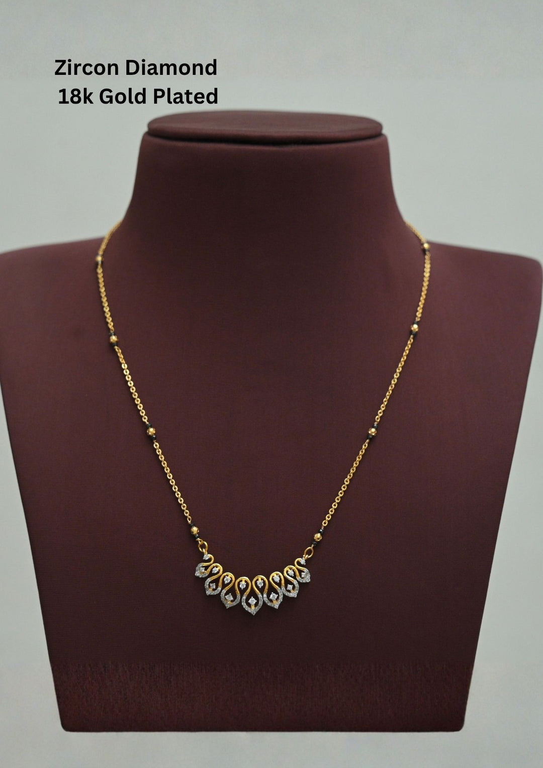 Modern Zircon Diamond gold plated mangalsutra necklace The design features a delicate gold link chain transitioning into sections of traditional small black beads on both sides. The central pendant showcases a sleek, contemporary curved V-shape and a stylized butterfly or floral motif encrusted with sparkling white cubic zirconia stones. This elegant neckpiece perfect for daily wear, office wear, and casual outfits.