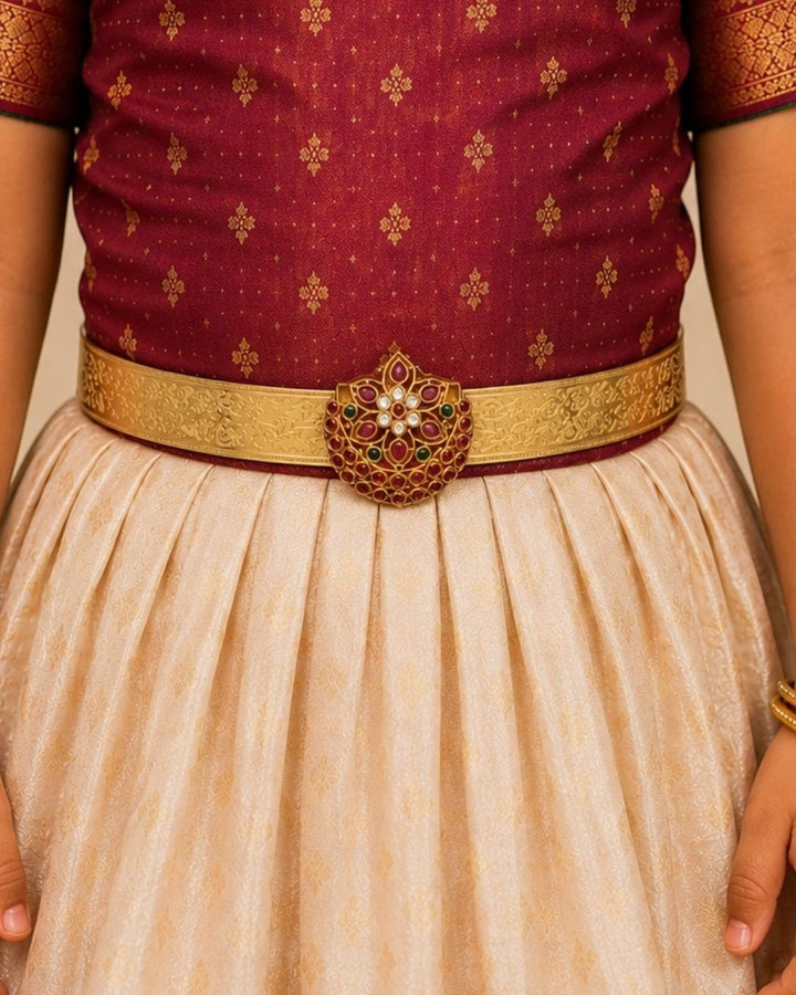 Beautiful gold plated hip belt featuring an intricately engraved wide band with a floral gemstone centerpiece accented with ruby, green, and white stones. Perfect for traditional wear, weddings, festive occasions, bridal styling, parties, and gifting.