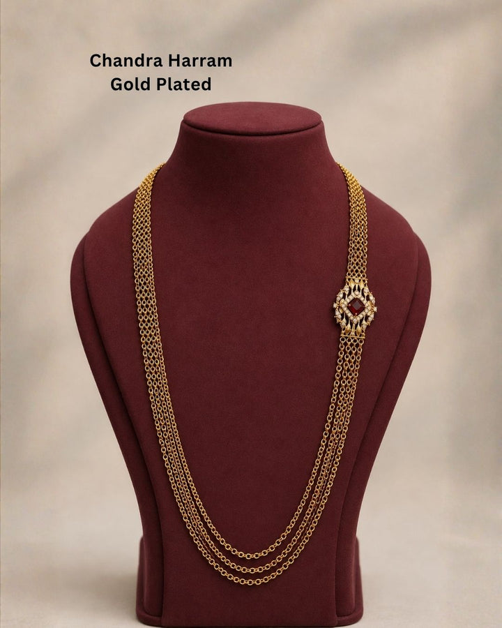 Beautiful ruby stone Chandra Haram gold plated necklace featuring multiple layered chains and an elegant red centerpiece with intricate gold and sparkling stone detailing. Perfect for festive occasions, traditional outfits, weddings, temple visits, and premium gifting.