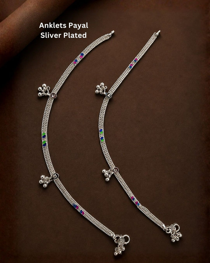 Beautiful silver plated multicolor anklet set featuring delicate layered chains, blue, pink, and green stone detailing, and dangling silver bead charms. Perfect for traditional occasions, festive wear, daily wear, and gifting.