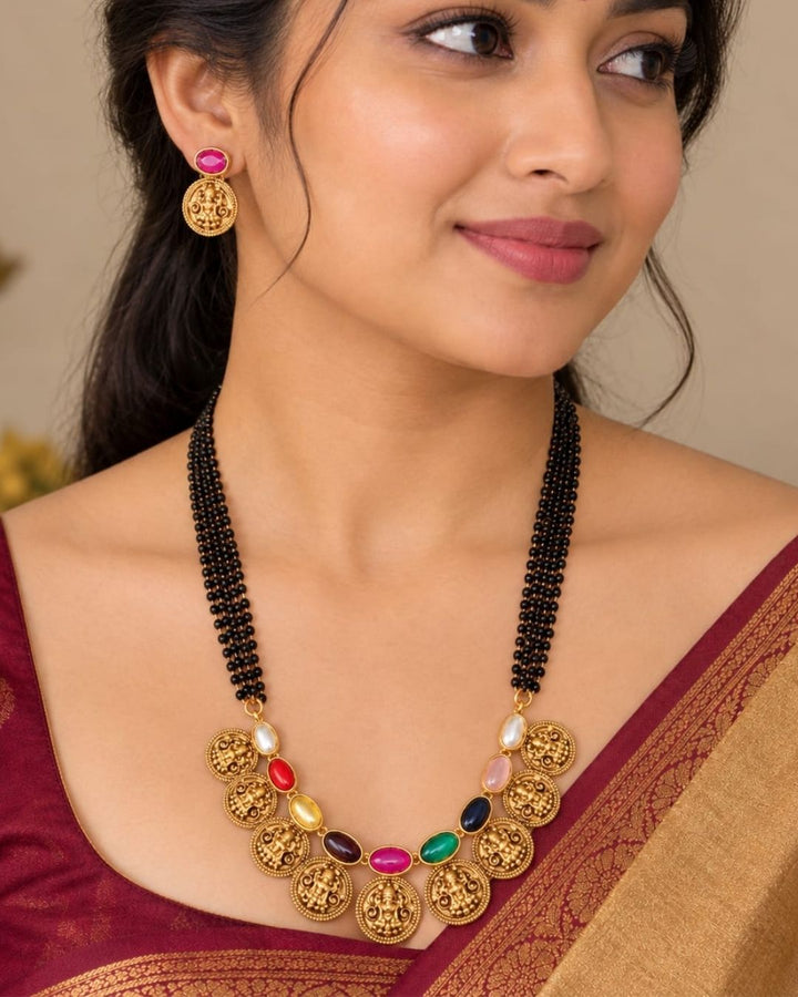 18k gold plated mangalsutra featuring a multi-strand black bead chain connected to a crescent of gold Lakshmi coins interspersed with colorful Navaratna gemstones. Includes matching gold Lakshmi coin earrings.