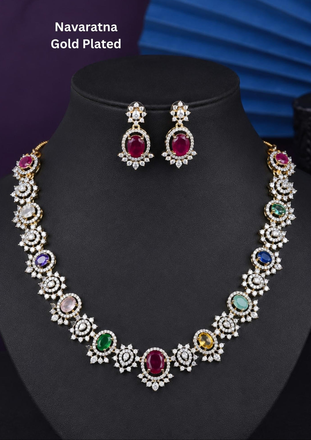 Premium gold plated Navaratna necklace set featuring vibrant ruby, emerald, sapphire, yellow, and pastel stones beautifully arranged with sparkling zircon accents. Comes with matching earrings, making it perfect for weddings, festive celebrations, and ethnic occasions.