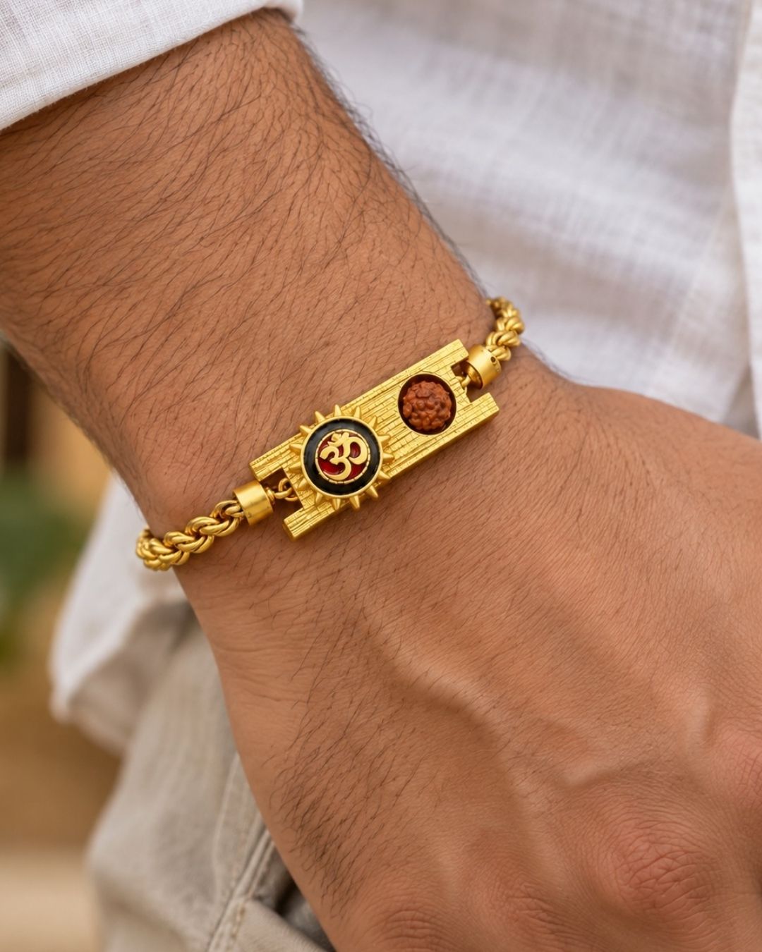 Elegant gold plated men’s bracelet featuring a prominent Om symbol, Rudraksha bead, ornate rectangular centerpiece, and braided gold chain, perfect for daily wear, festive occasions, and traditional styling.