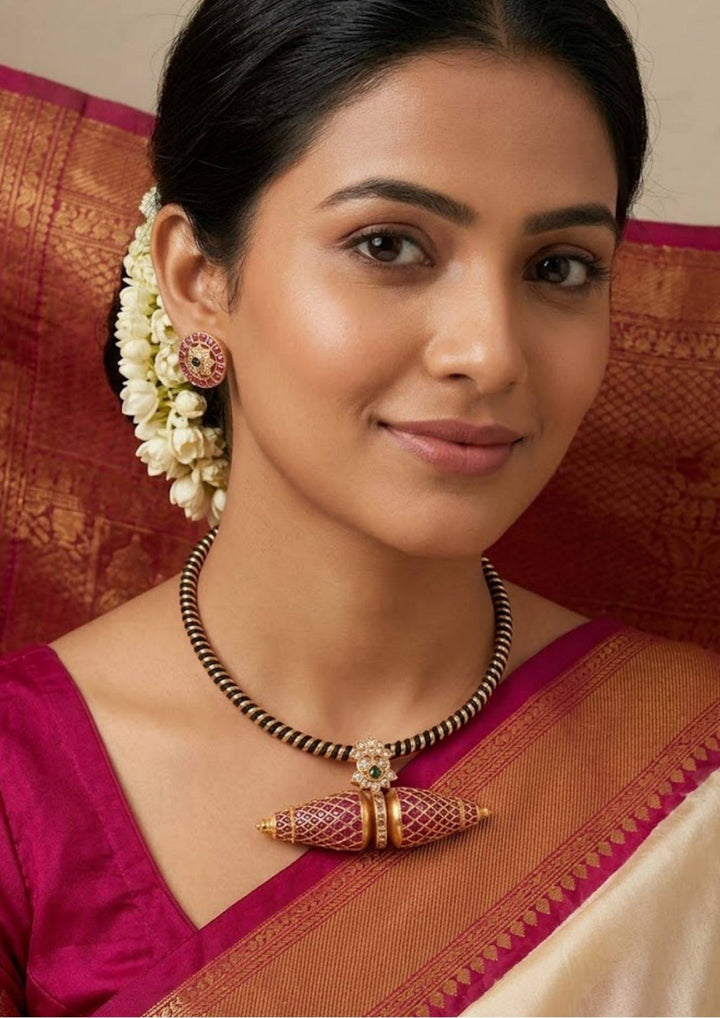 south Indian women wearing a kante necklace set with studs . Detailed view of the circular Kemp stone stud earrings and the matching Kante necklace pendant. The jewelry showcases premium antique gold plating, precise square-cut red stones, and central green accents, offering a sweat-proof, anti-fade, and high-quality traditional look for festive celebrations.