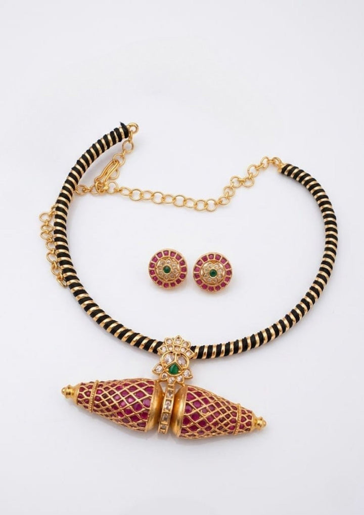 Detailed view of the circular Kemp stone stud earrings and the matching Kante necklace pendant. The jewelry showcases premium antique gold plating, precise square-cut red stones, and central green accents, offering a sweat-proof, anti-fade, and high-quality traditional look for festive celebrations.