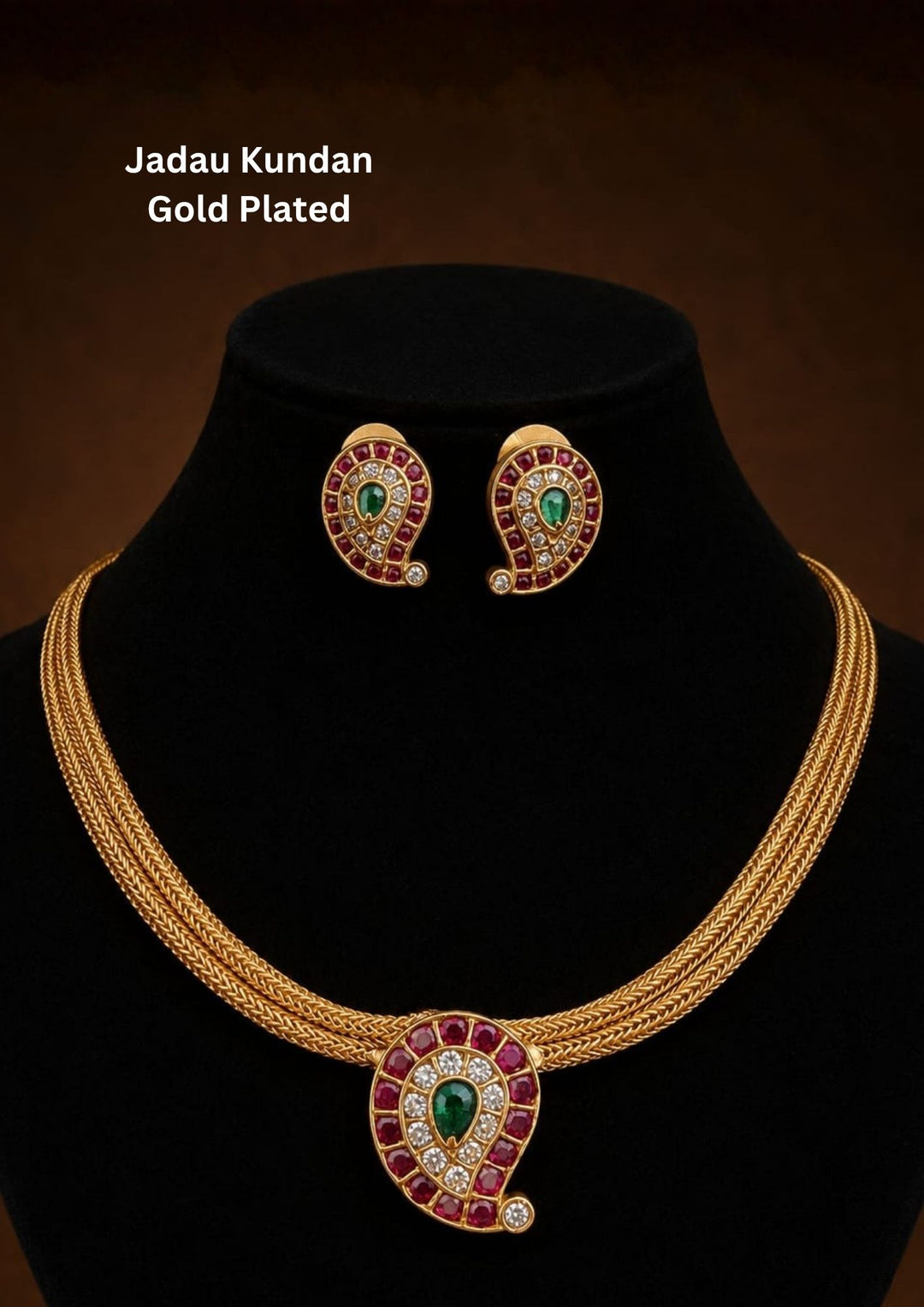 Beautiful Jadau Kundan gold plated pendant necklace set featuring a paisley motif with ruby red stones, a green center stone, sparkling kundan work, and matching earrings. Perfect for weddings, festivals, temple visits, traditional outfits, family functions, and premium gifting.