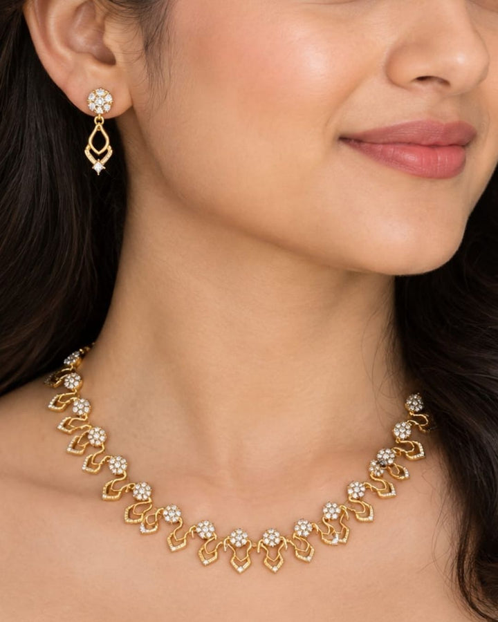 Modern south indian women wearing a, zircon diamond 18K gold-plated necklace and earring set showcasing delicate craftsmanship. The jewelry features sparkling diamond-like floral elements and curved drop shapes, making it a great choice to wear with sarees, lehengas, modern dresses, and festive wear for weddings, receptions, or family parties.