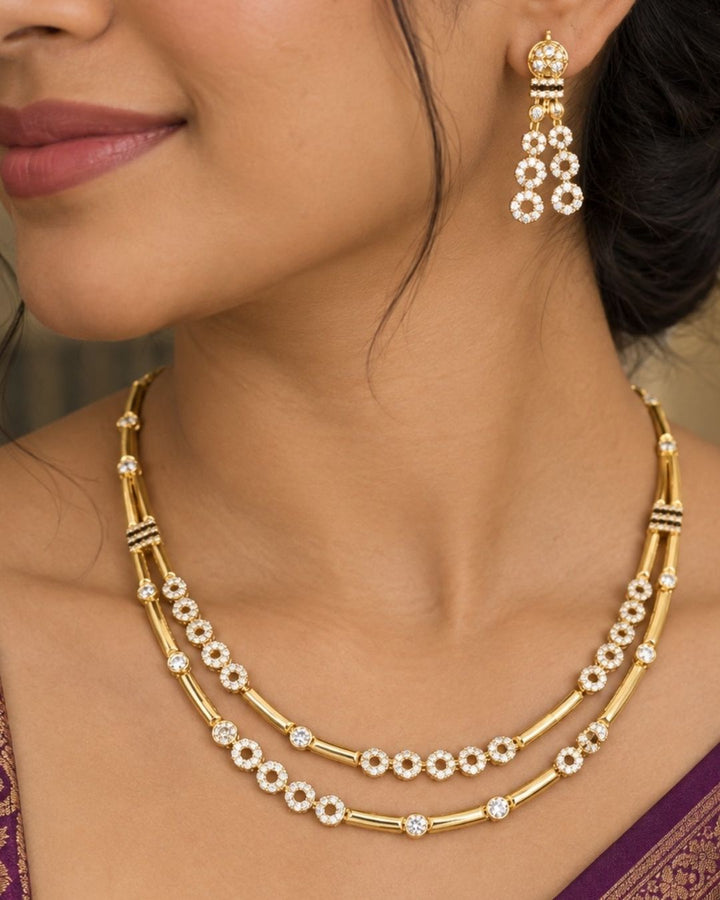 Stylish gold plated necklace set featuring layered gold-tone chains, sparkling circular stone embellishments, and matching dangling earrings, perfect for festive, party, and traditional occasions.