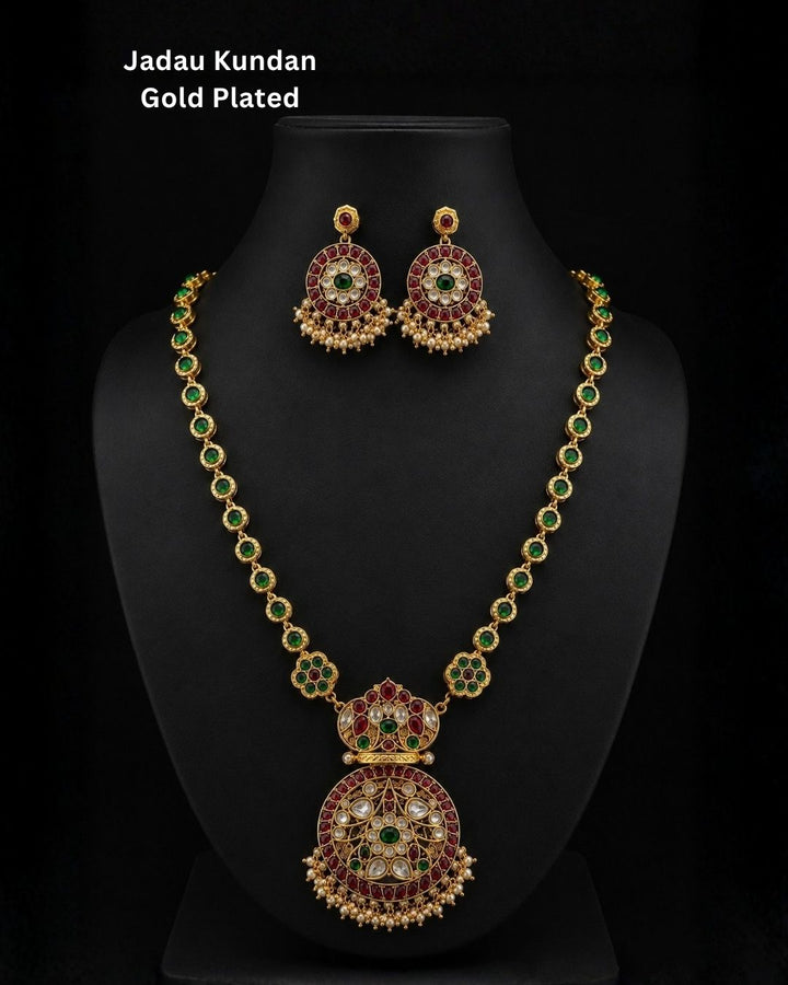 Premium gold plated CZ jewelry set with a ruby stone necklace, floral pendant, emerald green accents, pearl embellishments, and matching earrings for weddings and parties.
