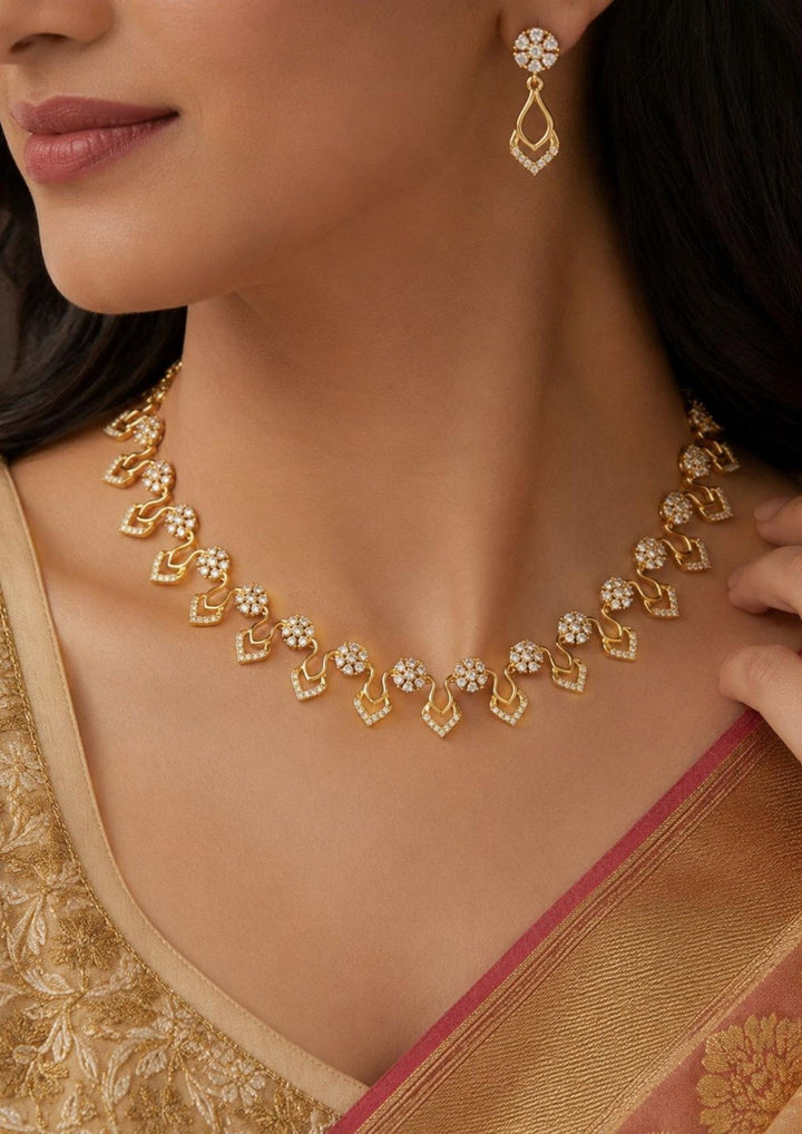 Modern south indian women wearing a, zircon diamond 18K gold-plated necklace and earring set showcasing delicate craftsmanship. The jewelry features sparkling diamond-like floral elements and curved drop shapes, making it a great choice to wear with sarees, lehengas, modern dresses, and festive wear for weddings, receptions, or family parties.