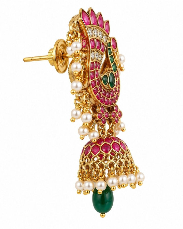 South Indian women wearing gold plated Jadau kundan jhumka earrings designed with an elegant pink ruby peacock pattern, shimmering kundan stone accents, and delicate pearl drop clusters that give a graceful traditional royal look for weddings, festive occasions, and temple visits with lightweight comfortable use