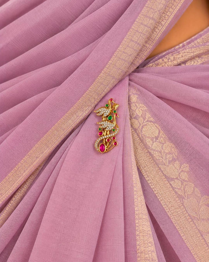 Pair of gold plated double peacock saree pins displayed on a light wooden surface, showcasing sparkling stones and decorative pin-back fastenings.