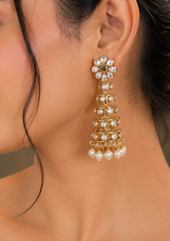 Close-up of a south indian woman wearing Gold Plated Traditional Jhumkas with dome-style buttalu pattern, colorful stone work, and pearl drops that give a grand bridal and festive jewelry look. The earrings come with lightweight comfort, sweat proof finish, anti-fade colour, smooth fitting, and are suitable for weddings, receptions, functions, and celebrations.