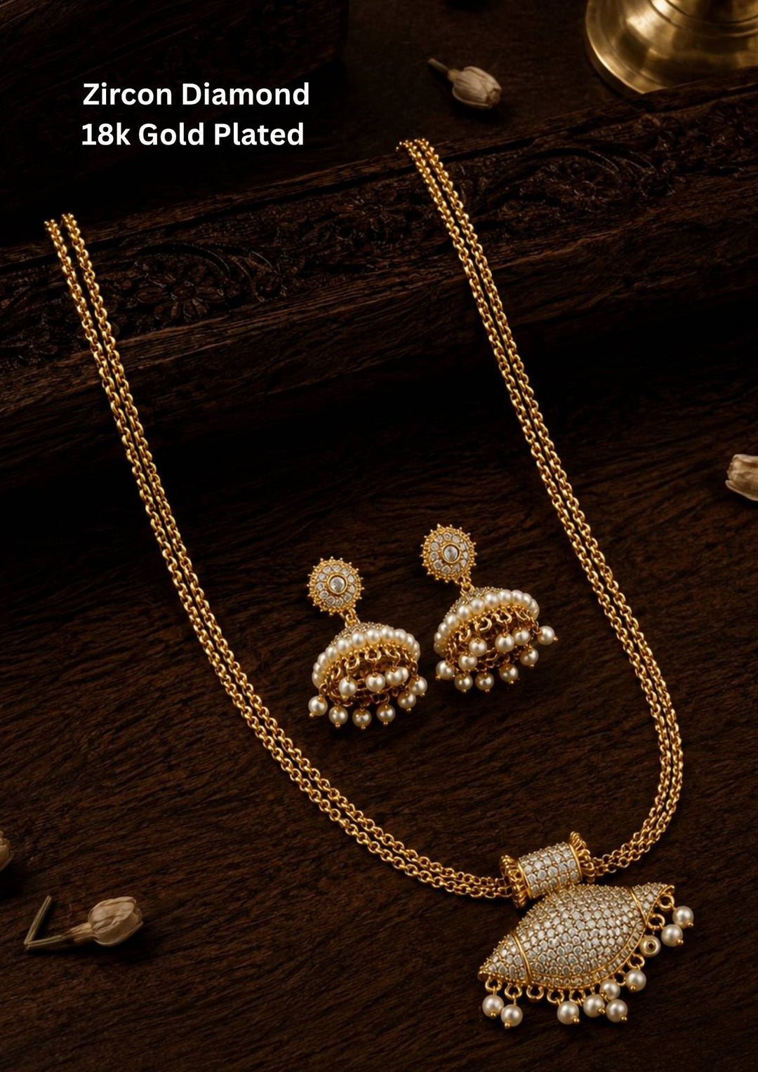 Elegant zircon diamond 18k gold plated necklace set featuring a dual layered gold chain with a detailed dome shaped pendant fully studded with tiny zircon stones and pearl hanging drops. The matching jhumka earrings have circular zircon tops with pearl bead danglers giving a rich traditional South Indian ethnic look suitable for weddings, festivals, poojas, sarees and lehengas.
