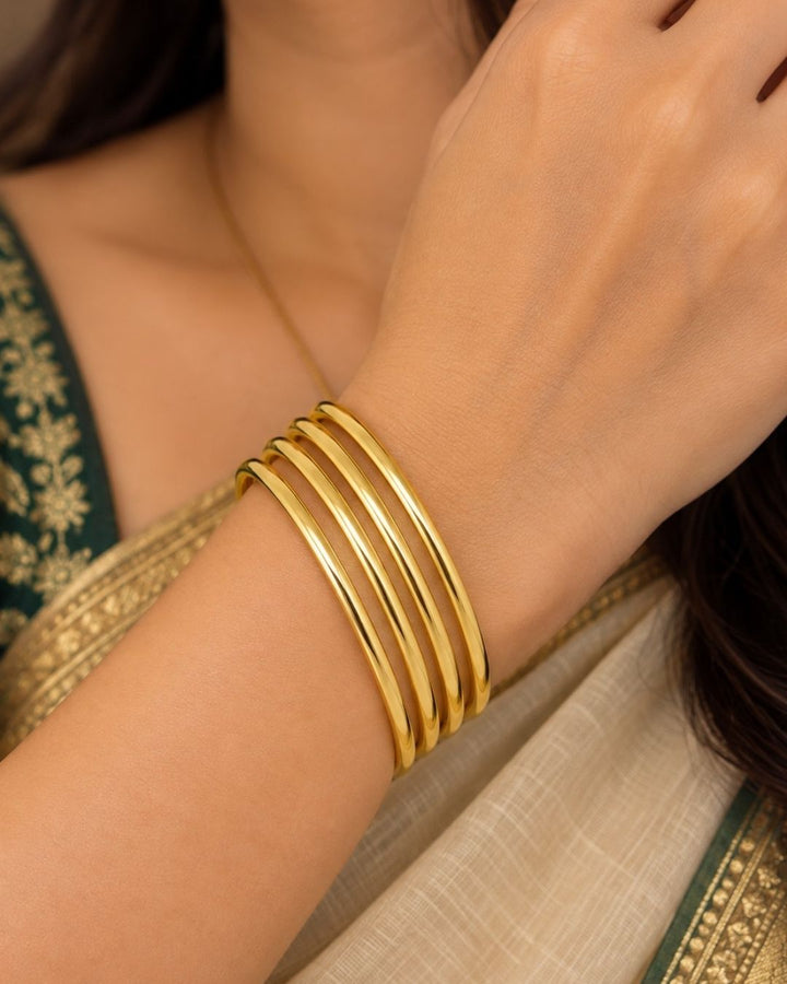 Four slim gold-plated rings stacked together Classic gold plated bangles with intricate engraved detailing for a timeless traditional look.