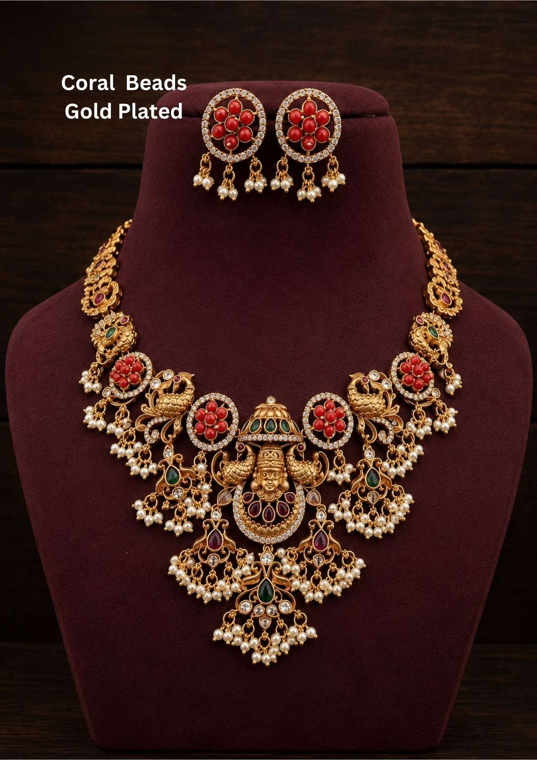 Coral beads gold plated Goddess Lakshmi long haar featuring a grand antique gold temple pendant with a central seated Lakshmi motif flanked by dual peacocks, red rubies, and green emeralds, suspended from a heavy four-strand chain of orange coral beads and white pearls. This long haram includes matching layered coral bell jhumka earrings topped with ruby studs, providing a rich and classy appearance suitable for weddings, temple visits, poojas, traditional functions with skin friendly quality