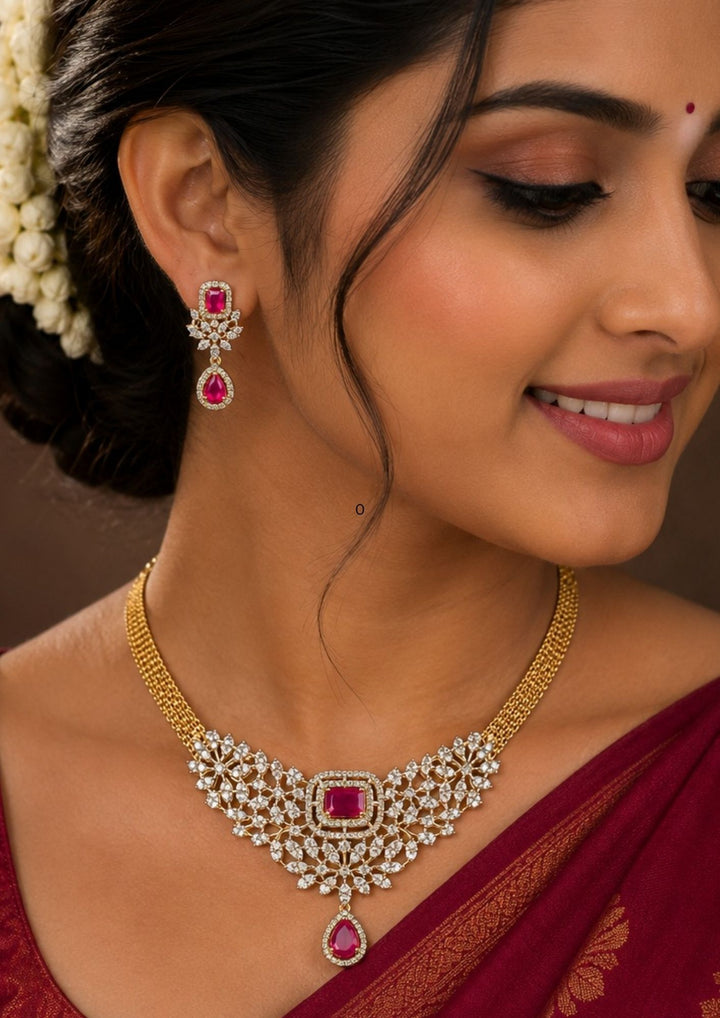 South Indian Woman wearing a Beautiful gold plated necklace set featuring sparkling zircon stones arranged in an intricate floral pattern with rich ruby-colored center stones. The design is completed with a ruby teardrop pendant and matching earrings for a graceful and elegant appearance ideal for weddings, receptions, parties and festive events.