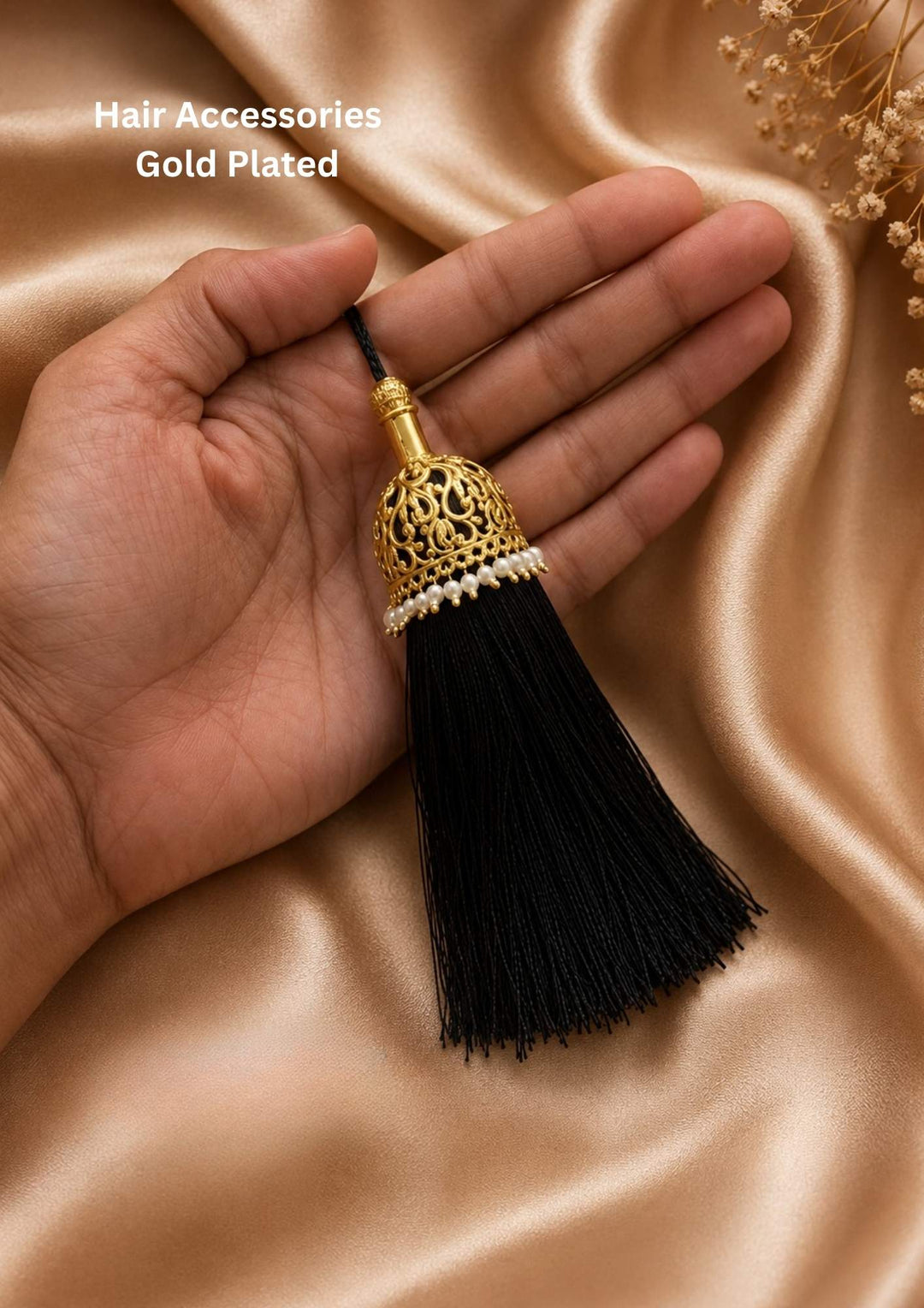 Gold plated hair accessory featuring a hollow, dome-shaped jhumka top designed with open gold net patterns. The lower rim of the golden dome is decorated with a single clean row of small white pearls, which connects to a long, thick hanging tassel made of fine black threads, providing a neat traditional look for festivals and weddings.
