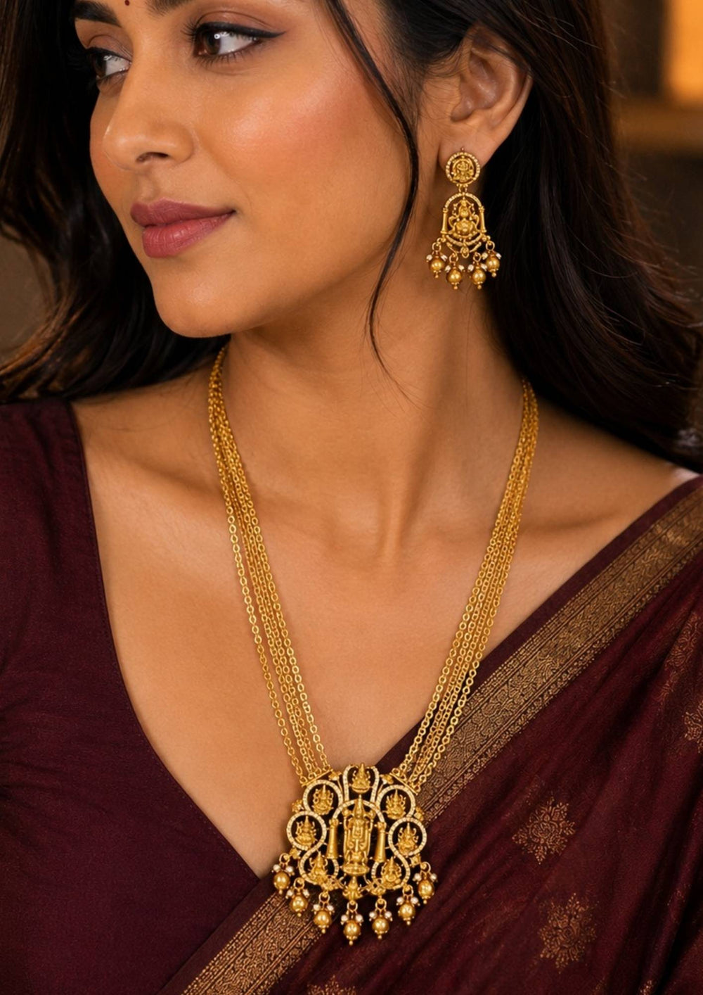 South Indian women wearing a Premium gold plated temple long haram featuring a grand Lakshmi pendant, four-layer chain design, intricate temple motifs, pearl drops, and matching Lakshmi earrings for traditional occasions.