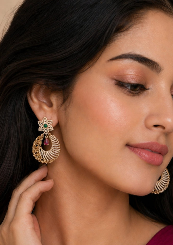 South indian women wearing Pure Zirconian Diamond Gold Plated Floral Earrings design with emerald and pink ruby stones the pattern on the left side of the earring is in flower shape and its perfect for weddings, office and its anti fade color