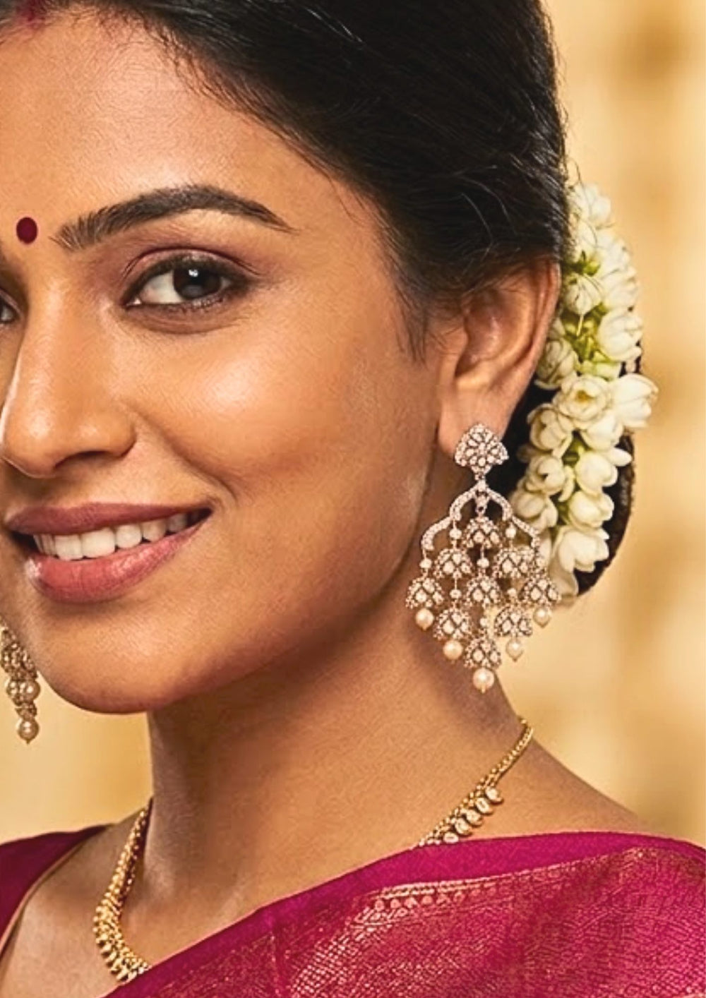 South indian Woman wearing a Detailed close-up view of the festive style gold plated American diamond step jhumka earrings. The skin-friendly, anti-fade gold finish earrings feature multiple layers of sparkling cz stone drops and hanging pearls, making it a perfect statement accessory for pairing with party wear lehengas, reception