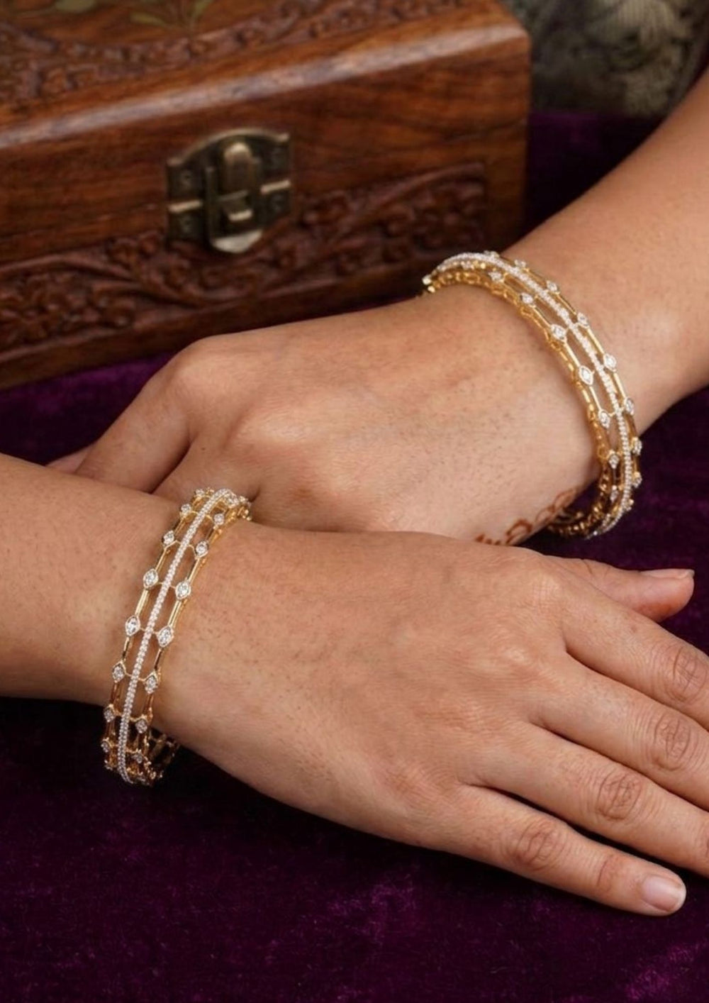 Close-up of a woman's hands elegant Pure Zirconian Diamond 18K Gold Plated bangles. Designed with a lightweight, three layer design with sparkling white stones, these premium finish bangles are suitable for daily wear, office styling, or festivals.