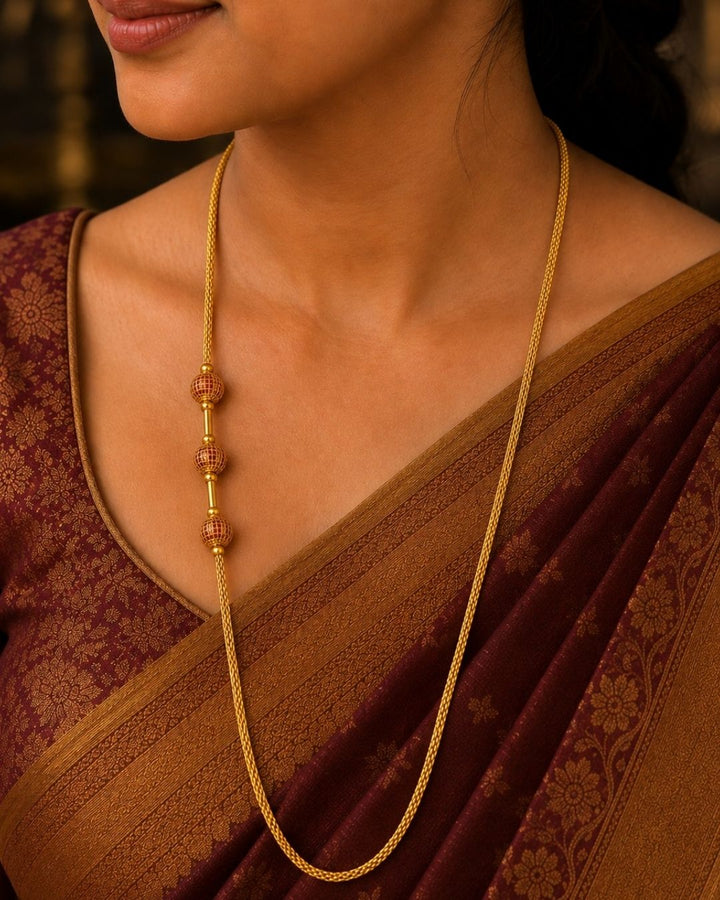 Stylish gold plated long chain featuring a fine textured design and three red and gold decorative beads. Perfect for traditional outfits, festive occasions, temple events, and special celebrations.