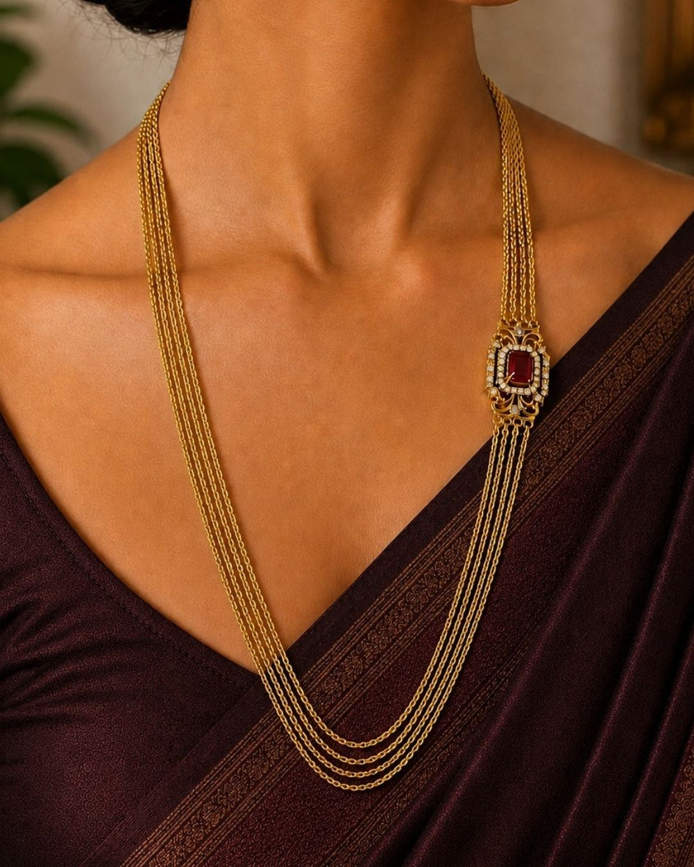 Beautiful multi-layer Chandra Haram gold plated necklace featuring a striking ruby-colored centerpiece with intricate detailing and sparkling accents. Perfect for festive occasions, traditional outfits, weddings, temple visits, and premium gifting.