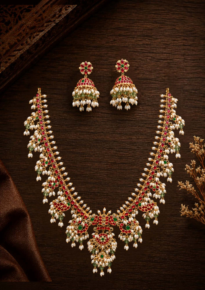 Gold-plated necklace set with intricate design long necklace Setand earrings  with rice beads green and red stones come with jadau kundan in necklace set  with beads and in pendent and earrings shows clear design and in detailed shown in picture it will not fade color and water proof can used for festivals, bridals, and weeding's  