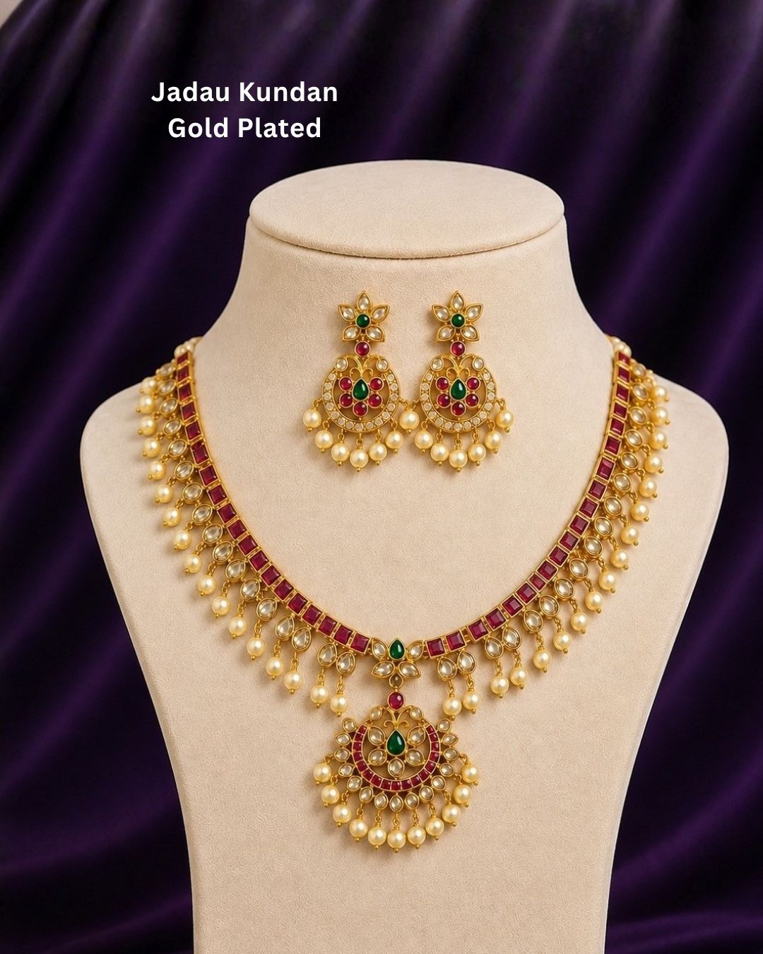 Beautiful Jadau Kundan gold plated jewellery set featuring a detailed necklace and matching earrings adorned with ruby, green stones, Kundan detailing, and pearl drops. Perfect for festive and traditional occasions.