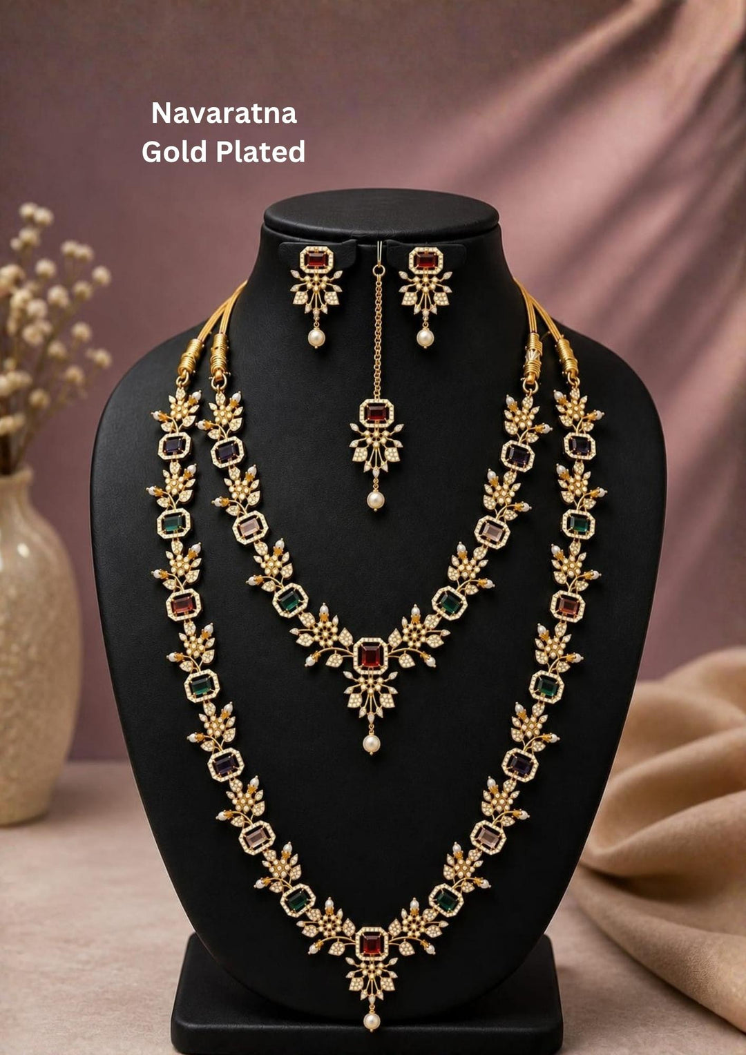 Beautiful gold plated Navaratna long haram set adorned with multicolor gemstones, floral designs, pearl drop accents, matching earrings, and a maang tikka. Perfect for weddings, festive occasions, traditional wear, and premium gifting.