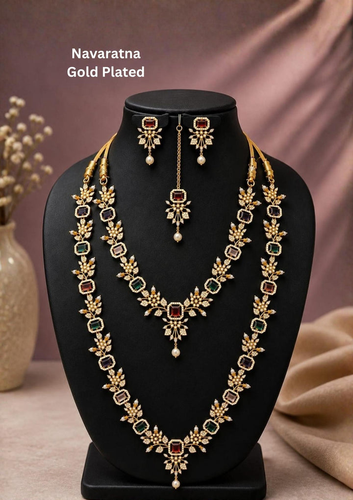 Beautiful gold plated Navaratna long haram set adorned with multicolor gemstones, floral designs, pearl drop accents, matching earrings, and a maang tikka. Perfect for weddings, festive occasions, traditional wear, and premium gifting.