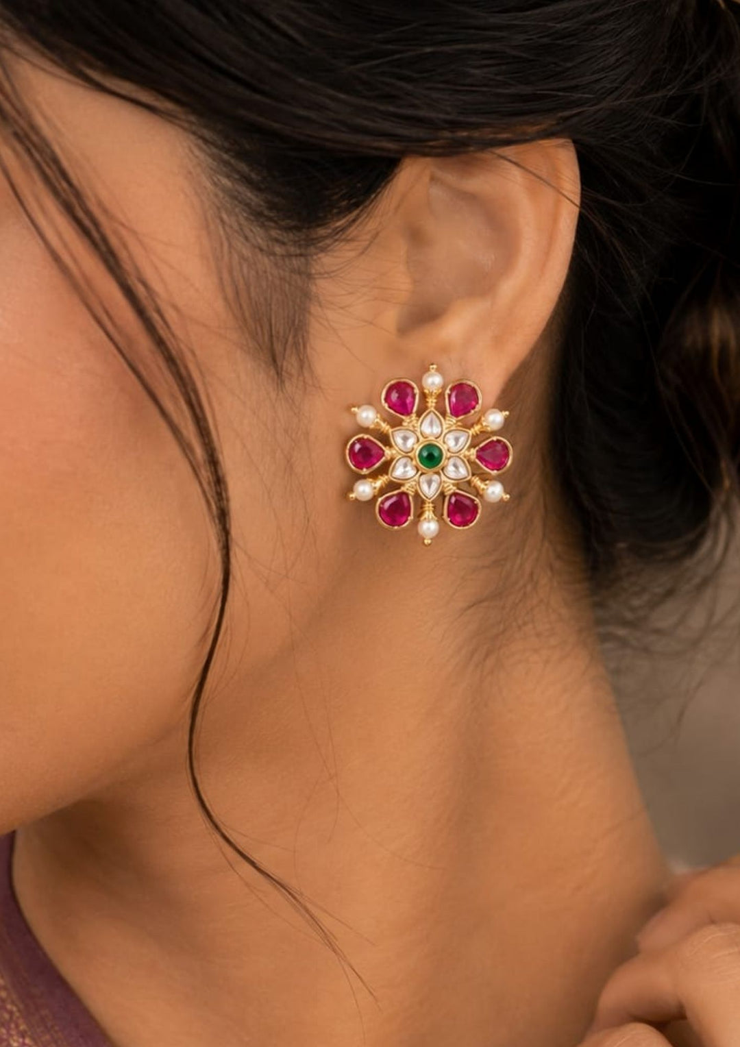 South indian Close-up of a woman wearing a floral earring with gemstones.