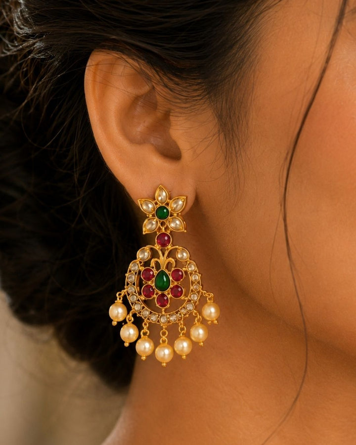 Beautiful Jadau Kundan gold plated jewellery set featuring a detailed necklace and matching earrings adorned with ruby, green stones, Kundan detailing, and pearl drops. Perfect for festive and traditional occasions.