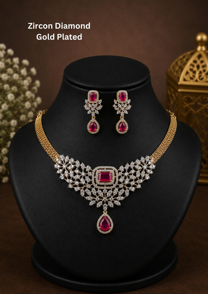 Beautiful gold plated necklace set featuring sparkling zircon stones arranged in an intricate floral pattern with rich ruby-colored center stones. The design is completed with a ruby teardrop pendant and matching earrings for a graceful and elegant appearance.