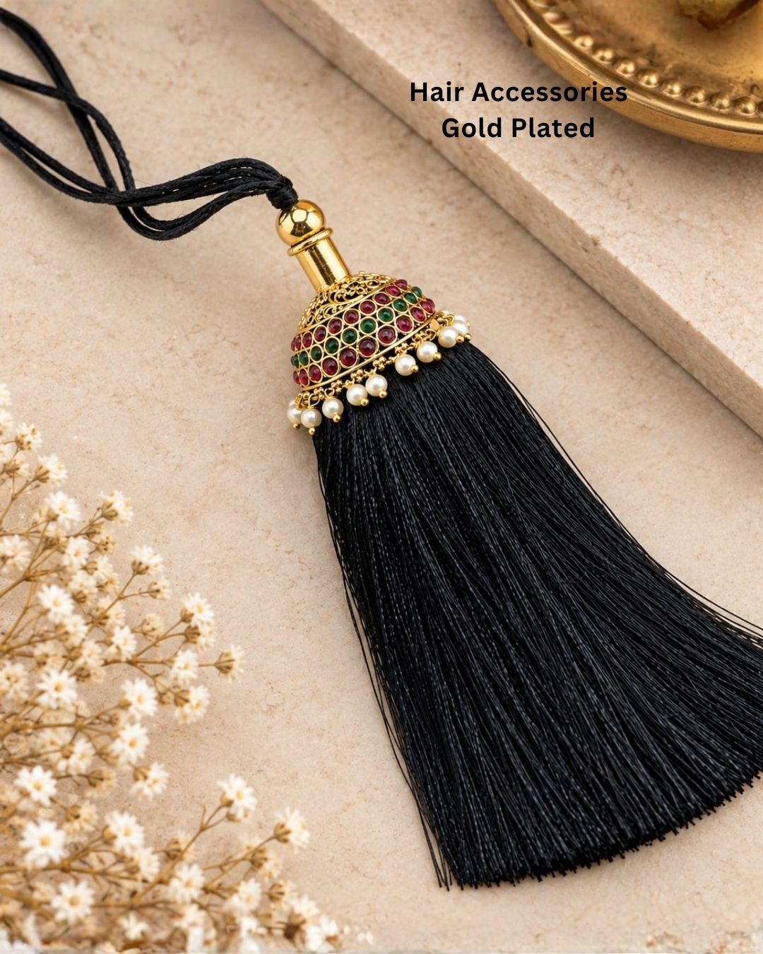 Elegant gold plated Jada Gantalu featuring a dome-shaped design with ruby and green stones, delicate pearl drops, and a long black thread tassel, perfect for bridal and festive hairstyles.