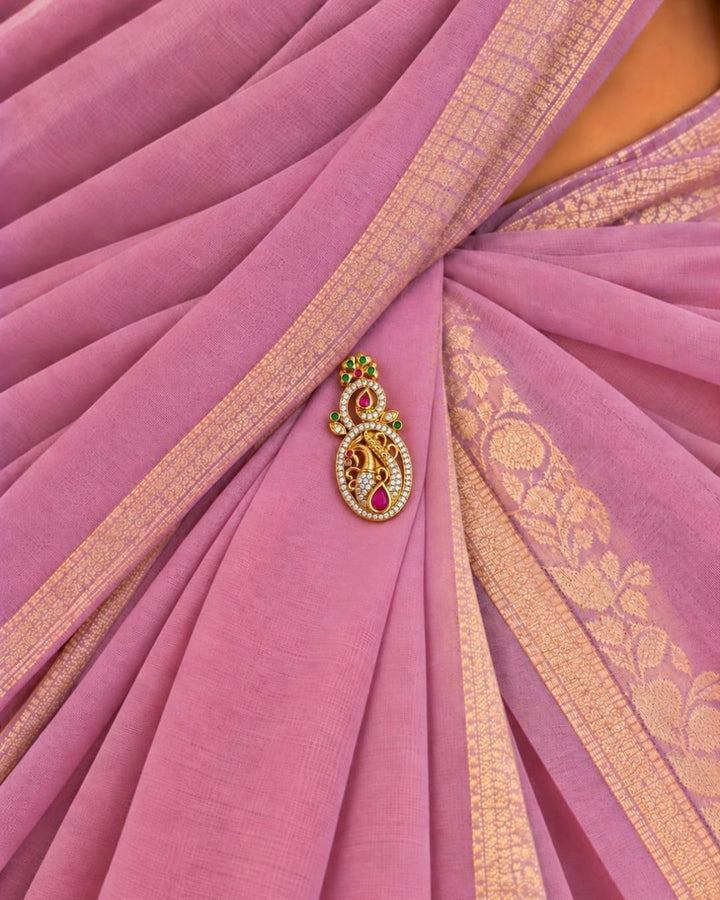 Pair of gold plated peacock design saree pins displayed on a light wooden surface, showing decorative front designs and secure pin-back fastenings.