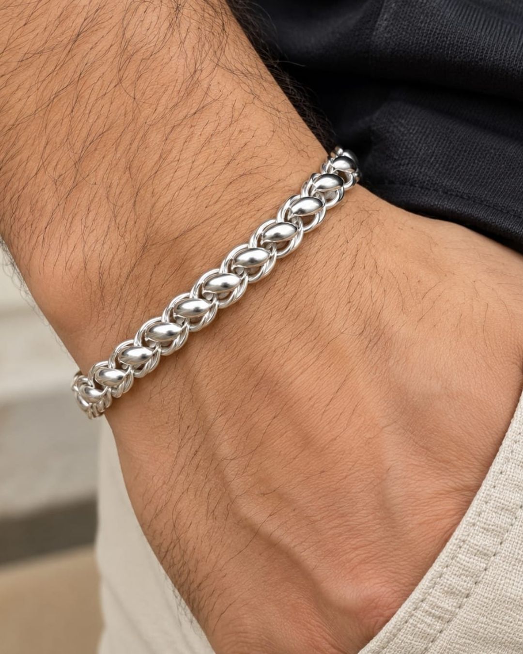 Premium silver finish men’s bracelet arranged in a circular shape on a black textured surface with decorative flowers.