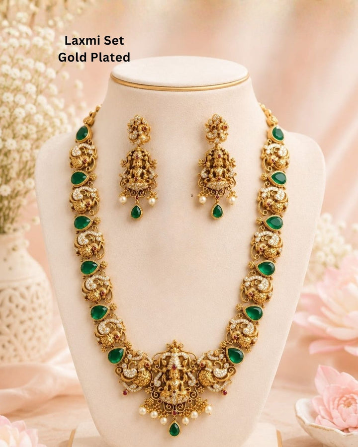 Premium antique gold plated temple necklace and earrings set crafted with intricate Ganesha and peacock designs, sparkling CZ stones, green accents, and elegant pearl details.