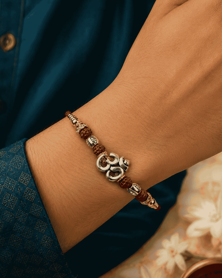 Premium Om Rudraksh Rakhi showcasing a silver-tone Om charm with Rudraksha beads, elegant metallic embellishments, and a handcrafted design for Raksha Bandhan.