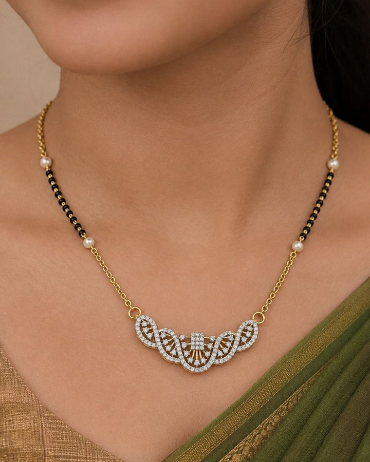 A close-up of a woman wearing a traditional Indian outfit, featuring a deep maroon saree with gold zari embroidery and a long, multi-strand gold necklace with red stone accents, along with a matching gold earring.