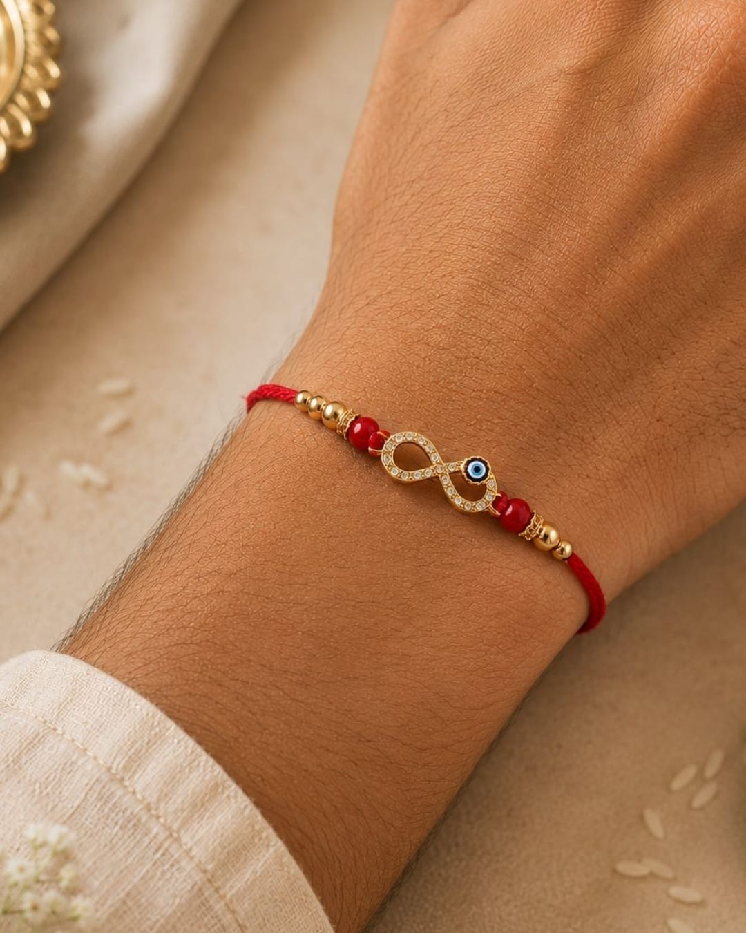 Premium Raksha Bandhan Rakhi showcasing an infinity symbol with an evil eye charm, decorative gold and red beads, and a vibrant red thread.