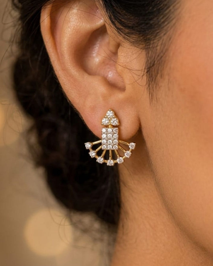 A close-up of a woman wearing a traditional Indian outfit, featuring a deep maroon saree with gold zari embroidery and a long, multi-strand gold necklace with red stone accents, along with a matching gold earring.