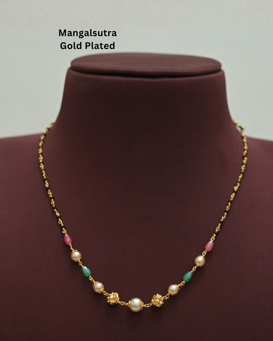 Traditional gold plated necklace featuring black beads, white pearls, green and pink stone accents, and decorative gold elements, perfect for ethnic and festive wear.